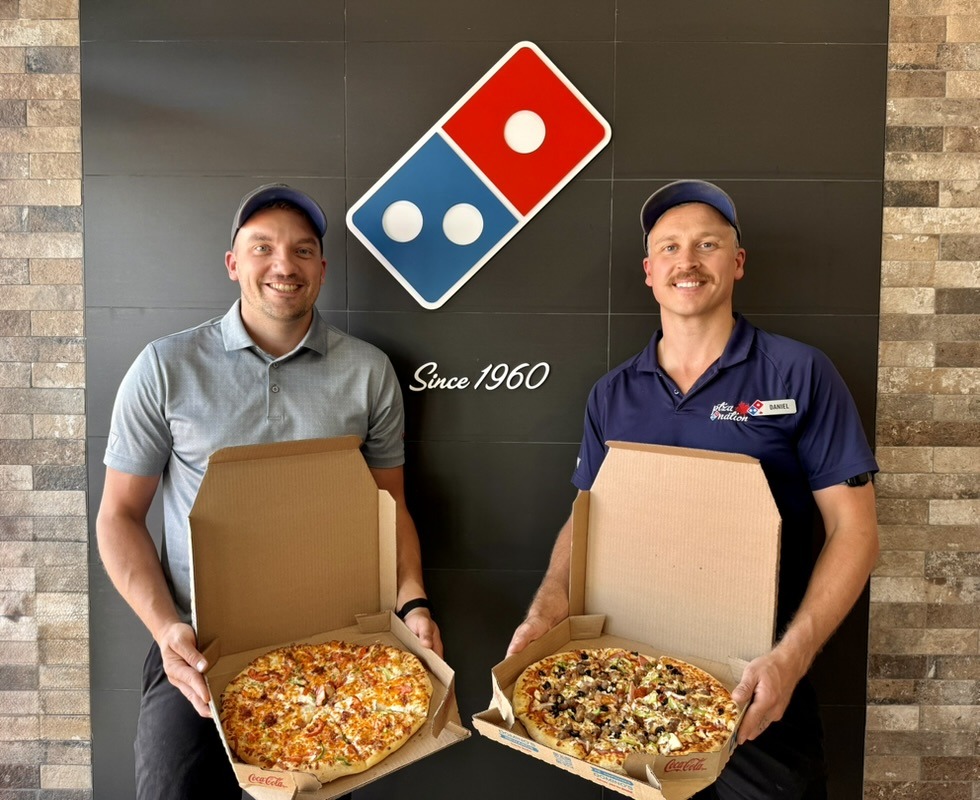 Louis Nelson and Daniel Tripp holding pizzas in a Domino’s store